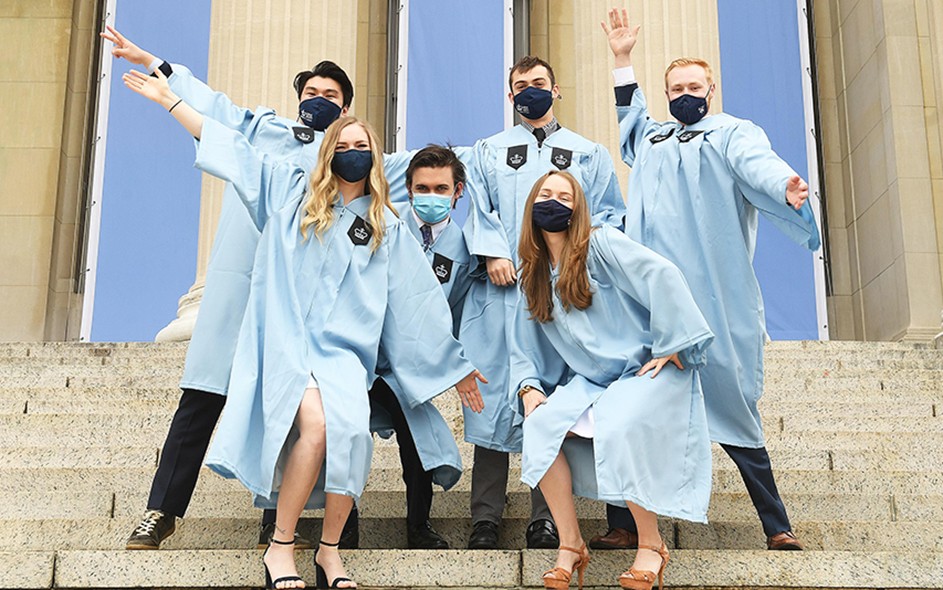 Masked Columbia grads in gowns pose on Low Steps. 