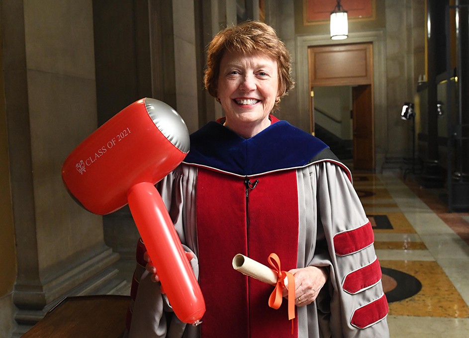 Mary Boyce in Commencement regalia with a hammer. 