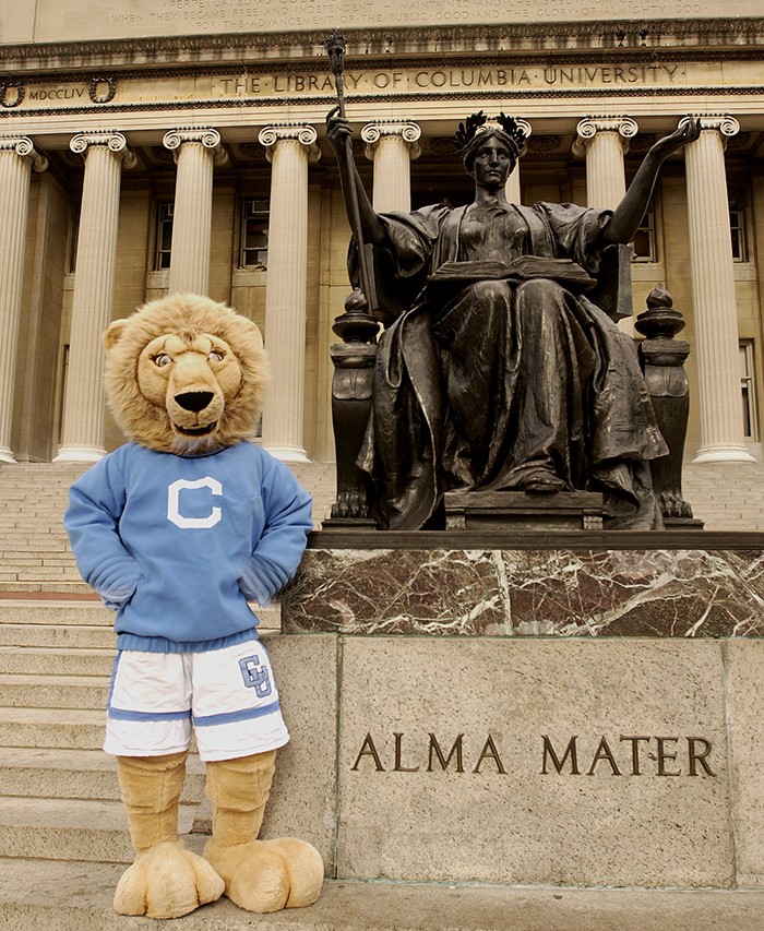Roar-EE in a sweater poses next to Alma Mater
