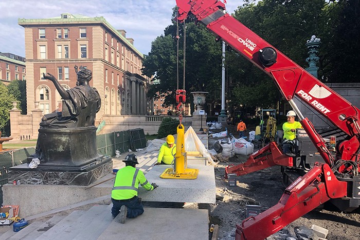 A small red crane replaces granite blocks behind the Alma Mater statue. 