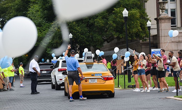 A taxi drives away amid a College WAlk lined with balloons.