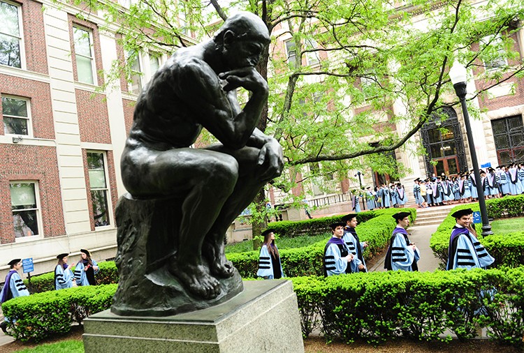 Graduates file past the Thinker statue on Columbia's campus. 