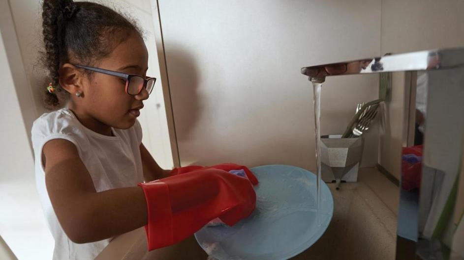 A child washing a disk in a sink.