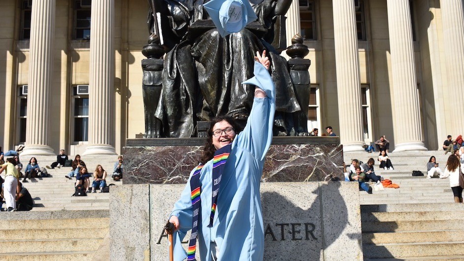 Leslie Zukor, (JRN'23) in her commencement regalia on the steps of Low Library in front of the statue of Alma throwing her mortar in the air.
