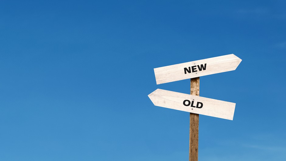 Stock image of two signs pointing in opposite directions on a post. One sign says "new," the other says "old."