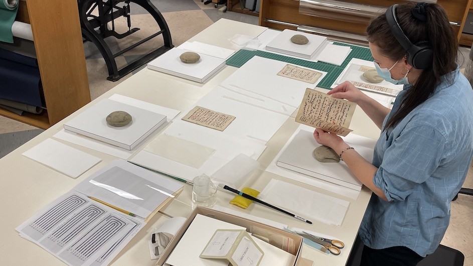Abigail Slawik mends the leaves of the antiphonary to prepare it for re-sewing.