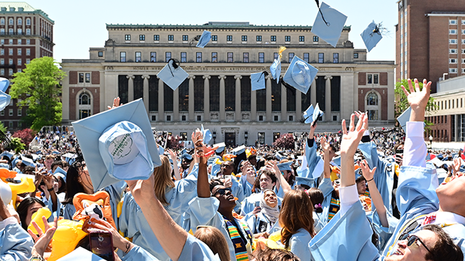 Columbia students toss mortar boards in the air.