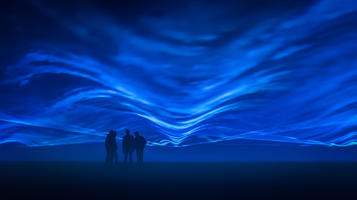 A few men standing in front of waves of blue light