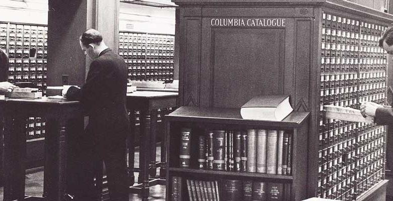 black and white vintage image of man standing at desk of columbia's butler library 