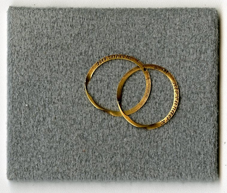 Two gold wedding rings on a gray background