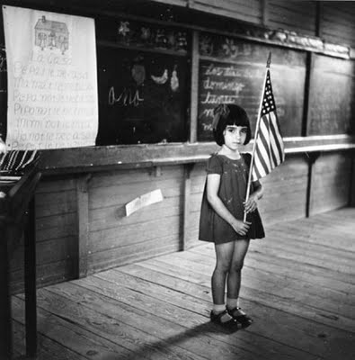 A little Puerto Rican girl in a classroom holding up an American flag. Photo Courtesy of the Delano Collection at Rare Book and Manuscript Library