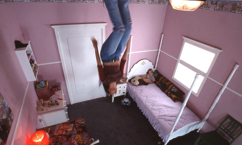 Woman walking on the ceiling of a pink bedroom