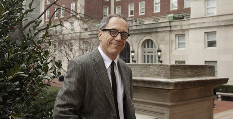 Image of Prof Hadju wearing a gray suit in dark rimmed glasses on the campus of Columbia University