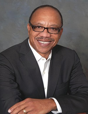 headshot of eugene robinson wearing a dark colored blazer with a white colored shirt underneath smiling directly into camera while wearing dark rimmed eyeglasses