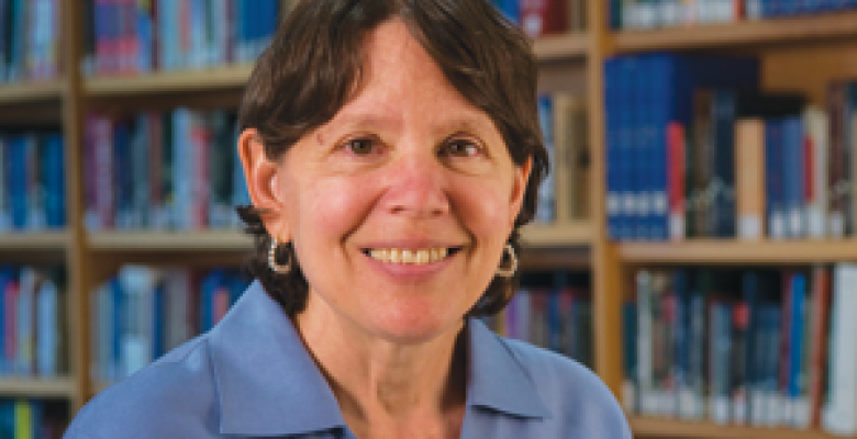 Professor Jane Waldfogel smiles into camera lens wearing a blue buttoned down collared blouse