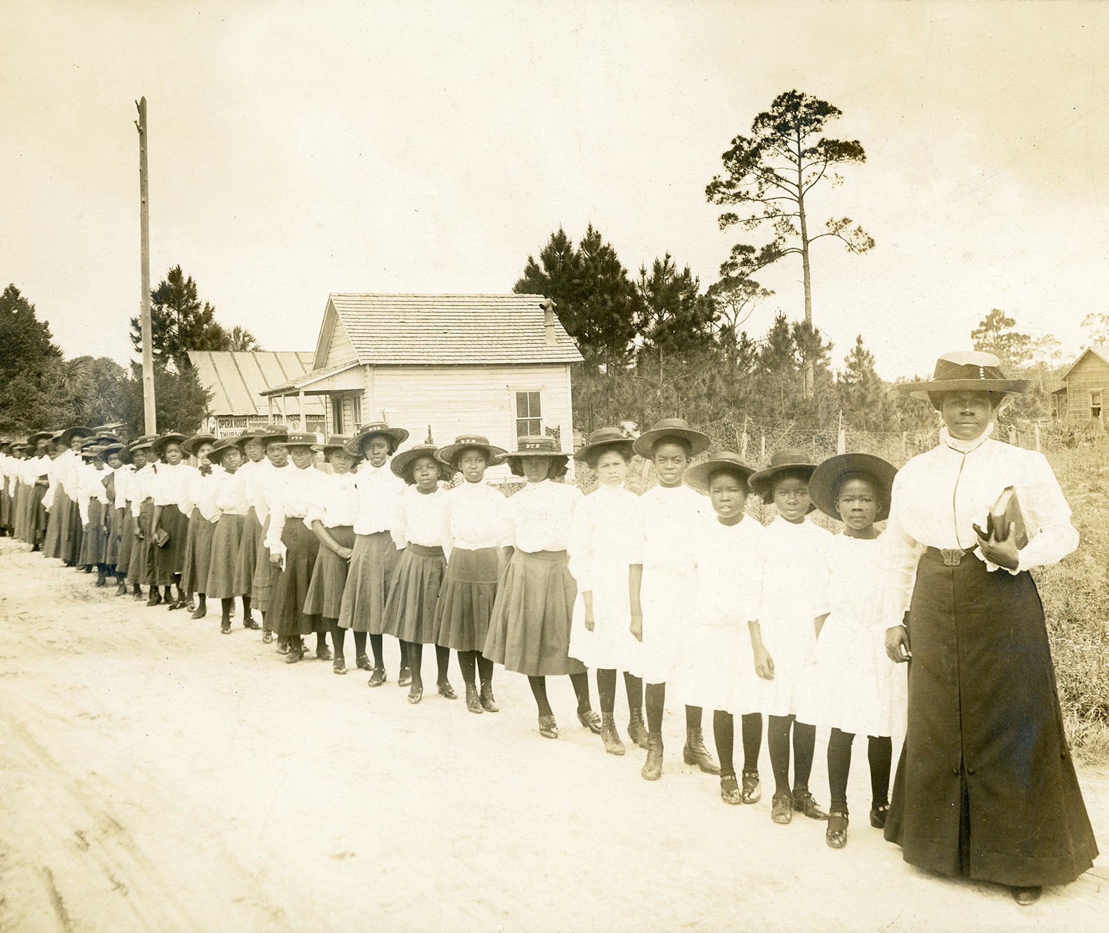 A diagonal line of African American schoolgirls and their teacher.
