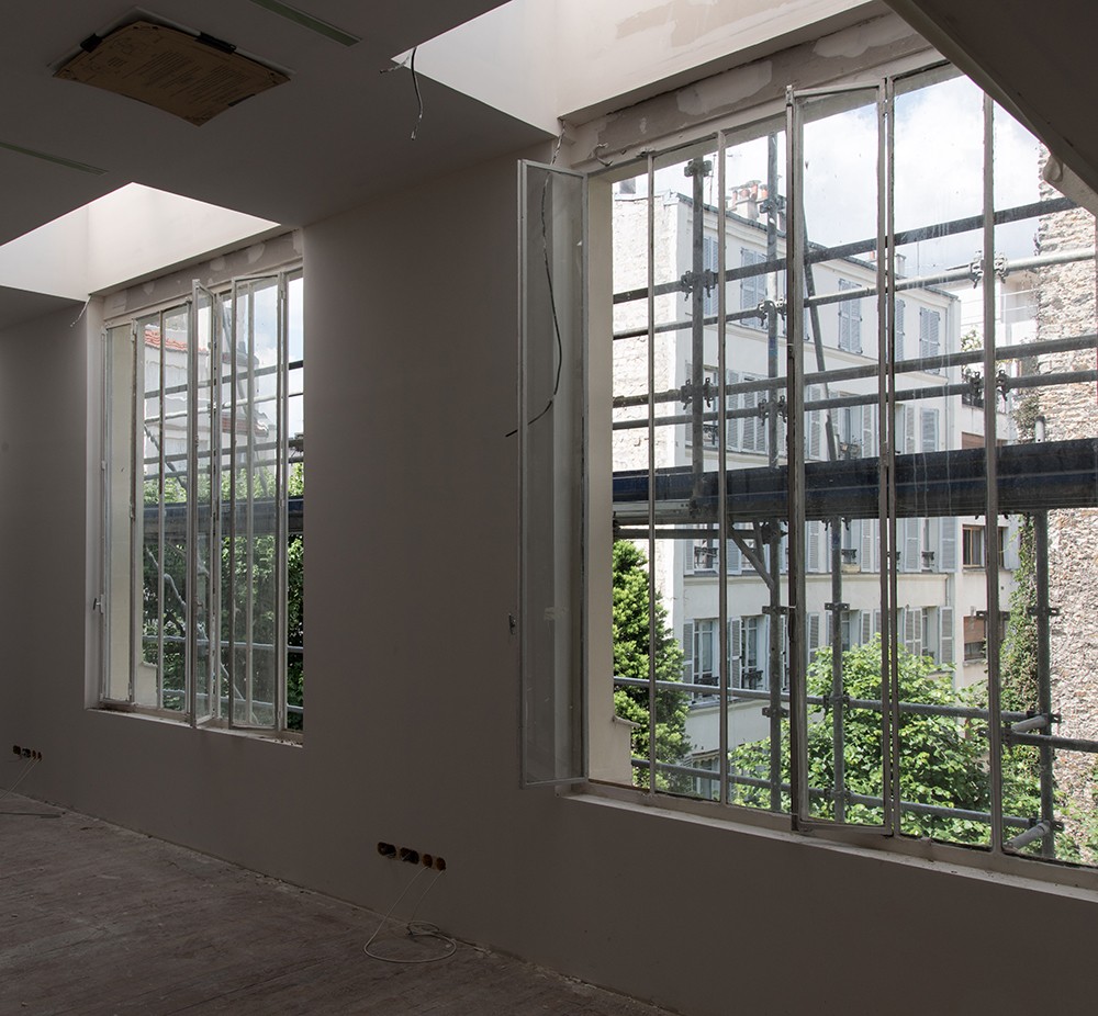 Photo of two windows from inside a building, showing scaffolding and construction