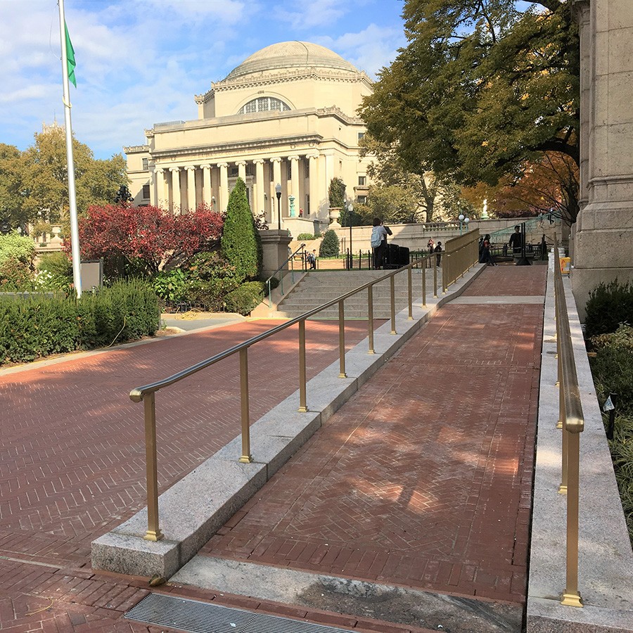 A masonry accessibility ramp leads to College Walk with a view of the Low Memorial Library in the background. 