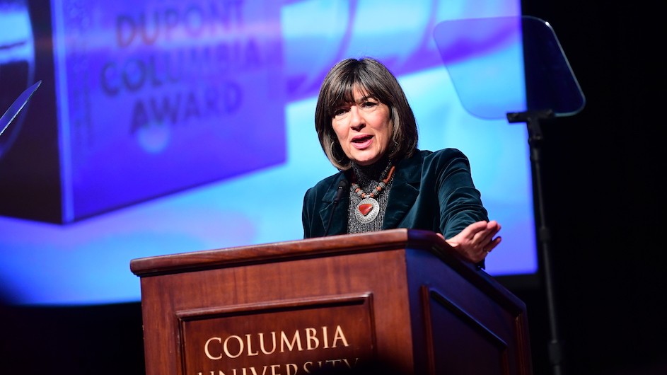 Woman speaking at podium with screen saying DUPONT COLUMBIA AWARD in background