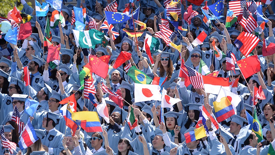 A crowd of students waive international flags at Columbia's annual Commencement