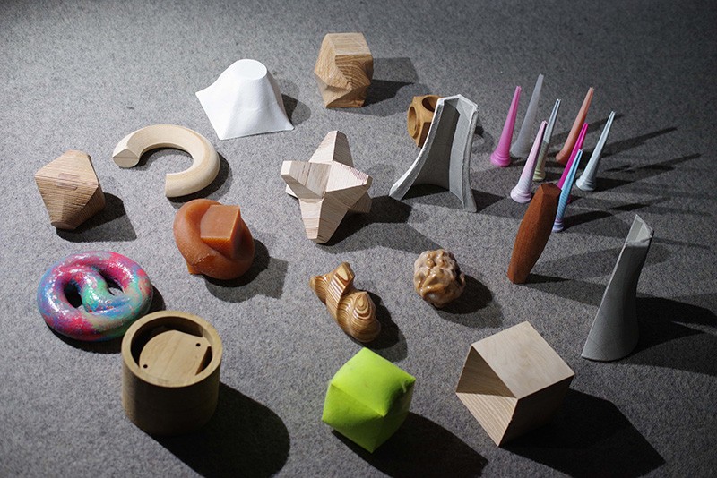 A collection of materials used in the Fabrication Lab--clay, plastic, wood, paper-- are arranged on a table.