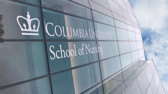 An image of the reflective facade of Columbia's School of Nursing, with the schools logo, featuring a stylized crown