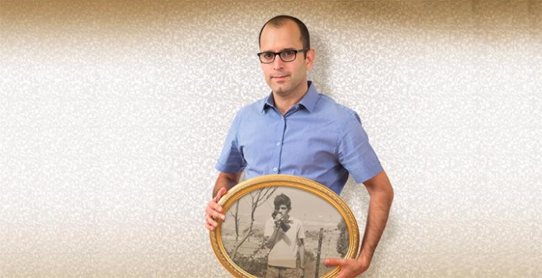 Yaniv Erlich holds a framed picture of his father as a teenager