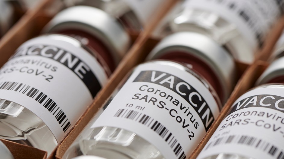 Numerous vials of vaccine with black and white labels
