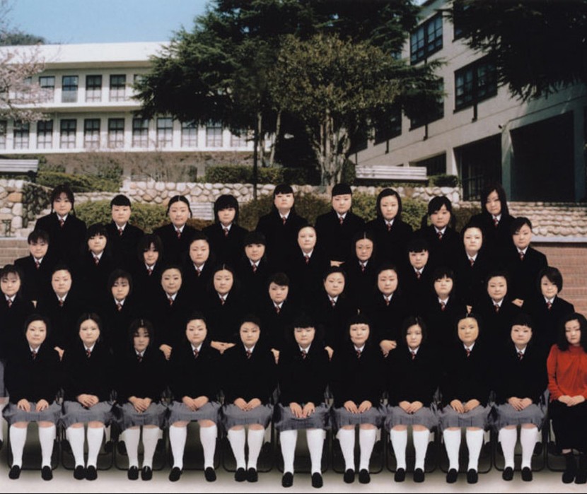 Rows of Asian school girls in uniform face the camera.
