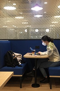 young Asian woman typing at a computer desk in brightly lit room