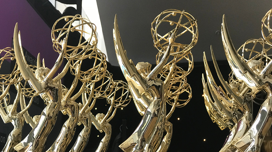 A lineup of Emmy awards on a table. 