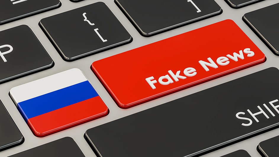 A detail of a computer keyboard with a red key that says Fake News next to a key with the Russian Federation flag (white, blue, and red stripes).