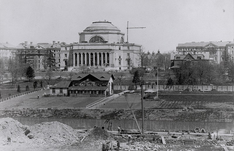 a vintage black and white distant image of low library appearing to be completely constructed. Area surroudning the Low area is mainly dirt filled and under construction while men are at work on the grounds.