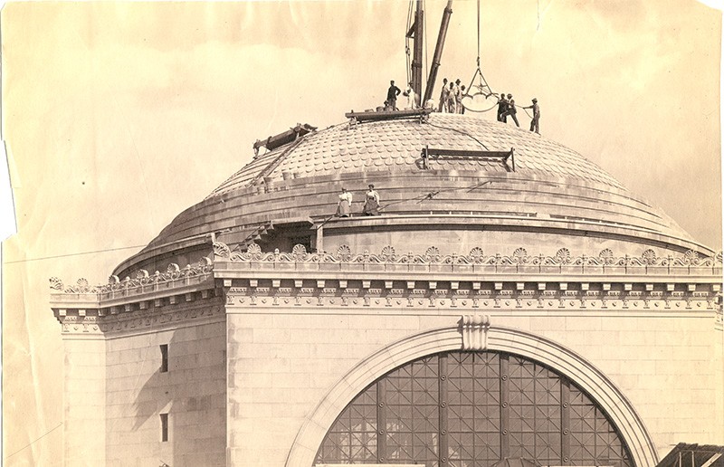 a sepia toned vintage image of low library showcasing men at work on the top dome area of low library. 