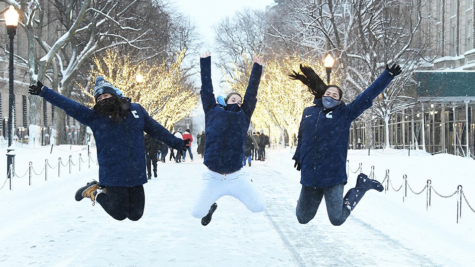 Three Columbia students jump in the snow on College Walk in February. 