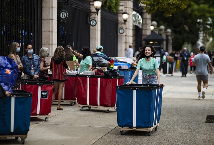 A Barnard student walks a bin full of move-in essentials into her dorm. 