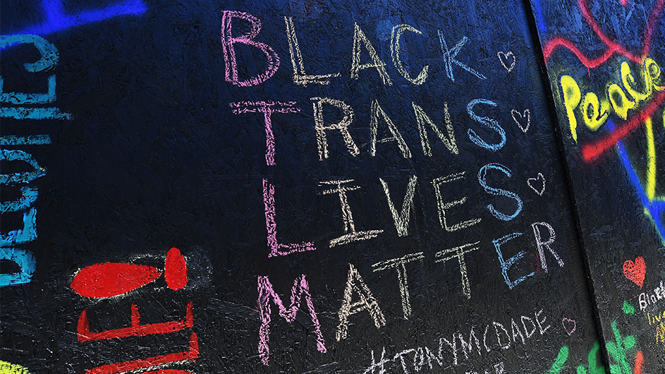 "Black Trans Lives Matter" is graffitied on a black wall in Harlem.