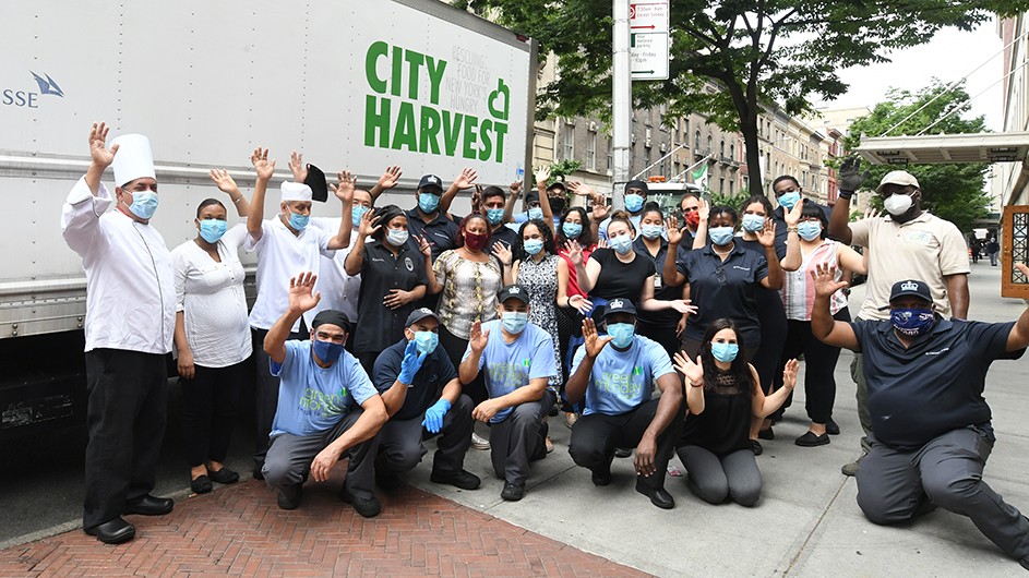 A group of Columbia Dining works gather around a City Harvest truck with masks on.