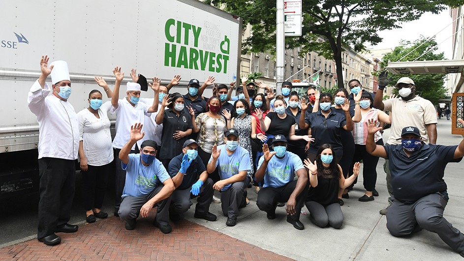 Photo by Eileen Barroso A group of Columbia Dining works gather around a City Harvest truck with masks on.