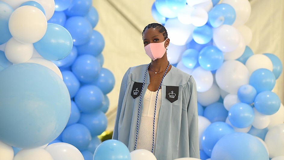 A woman in Columbia regalia is surrounded by blue and white balloons. 