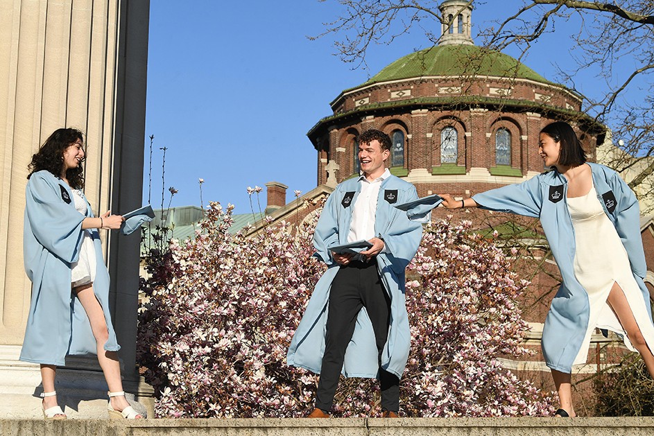 Photo by Eileen Barroso Three grads pose on Low Steps with magnolias trees behind them.