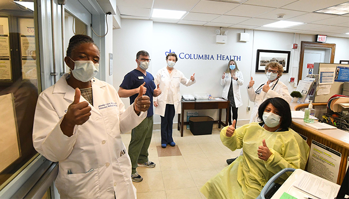 Columbia Health workers in PPE give a thumbs up. 