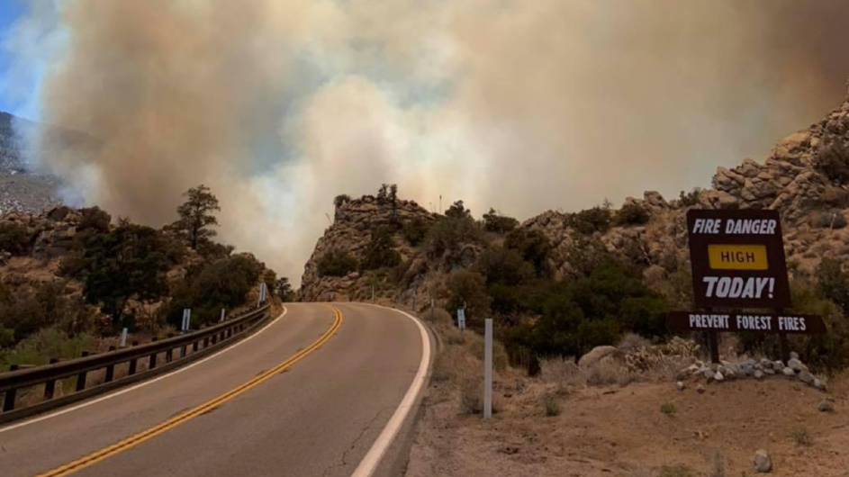 Smoke from the Flats Fire in Pinyon Pines, CA, on June 13, 2021. Photo: Lisa Cox/USFS A sign warns of fire danger at a national park as a wildfire burns in the background.