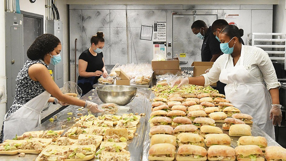 A line of sandwiches stretches from Columbia Dining workers preparing food packages for the community.