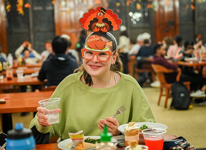 A student with a turkey mask on in gobbles food. 