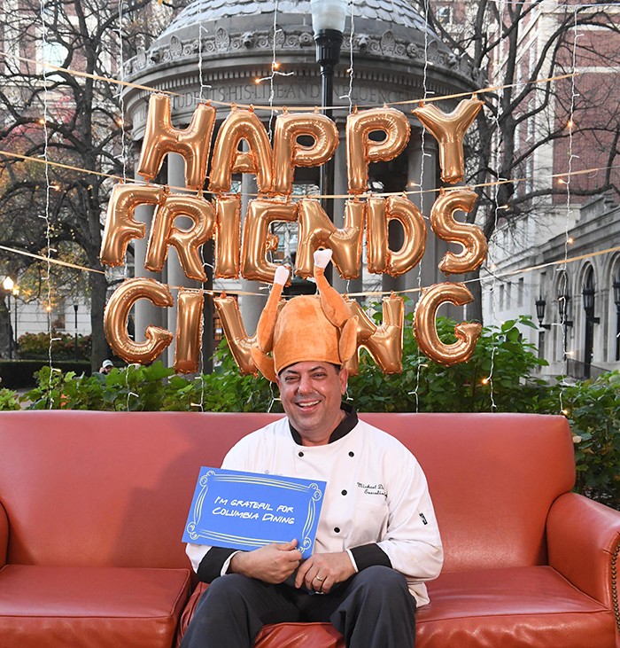 Columbia Dining's Chef Mike in a turkey hat on an orange couch on Van Am Quad. 