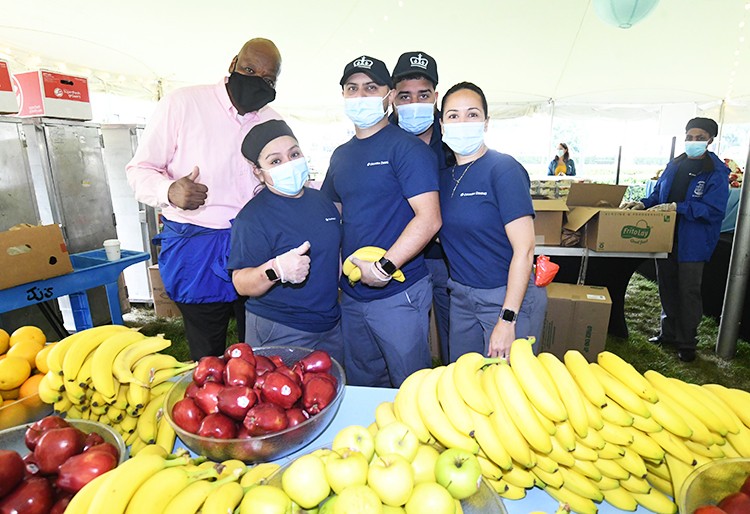 Photo by Eileen Barroso Columbia Dining staffers stand with a table full of bananas and apples.