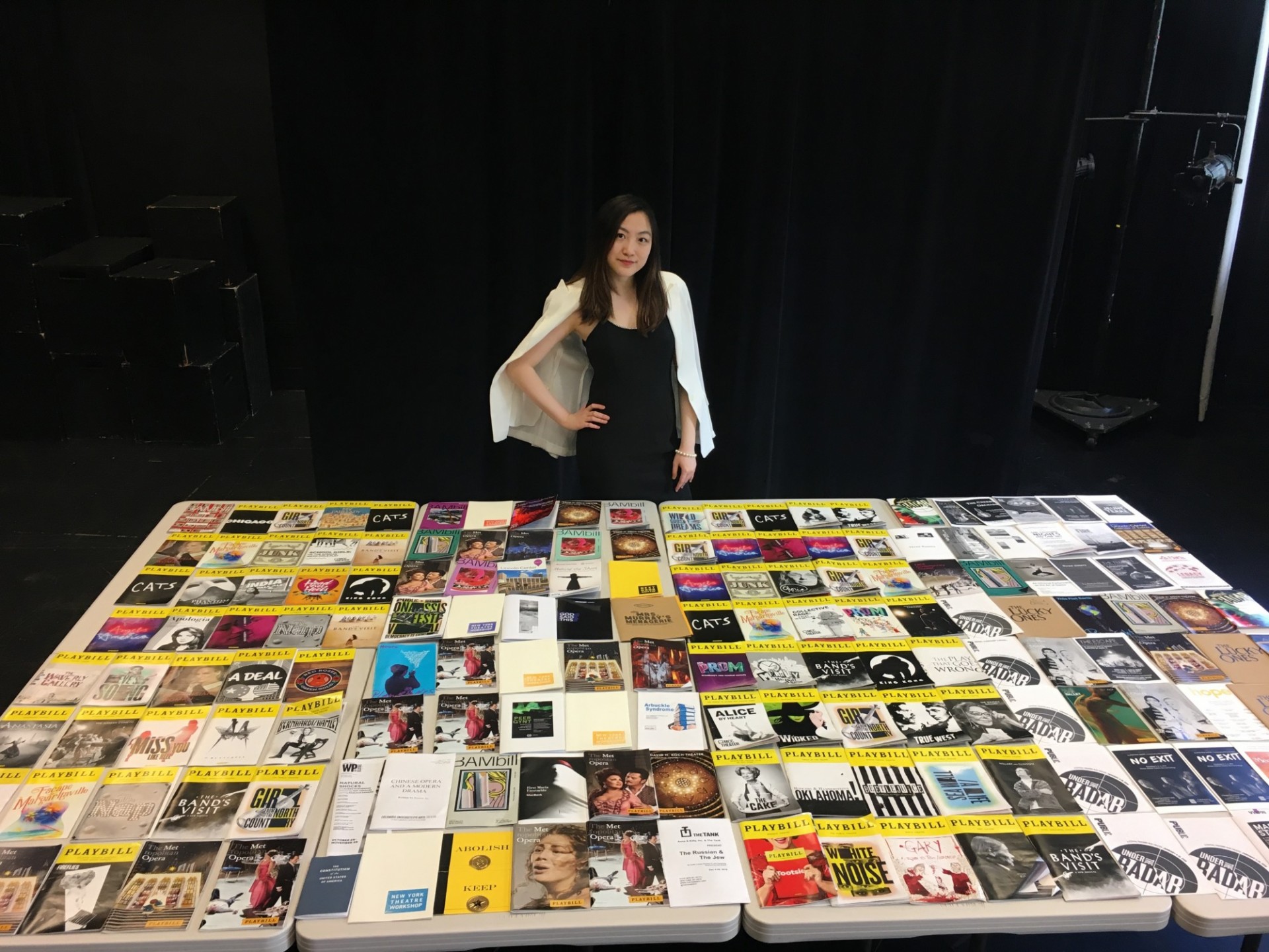 Genevieve Wang stands with a table full of Playbills.