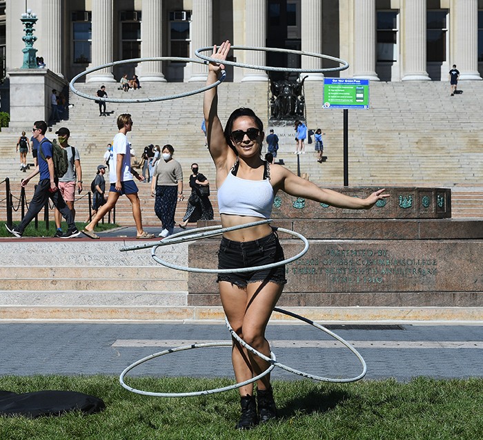Maia Oceana Castro-Santos (CC'25) spins hula hoops in front of Low Library. Photo by Eileen Barroso/Columbia University. Maia Oceana Castro-Santos (CC'25) spins hula hoops in front of Low Library.
