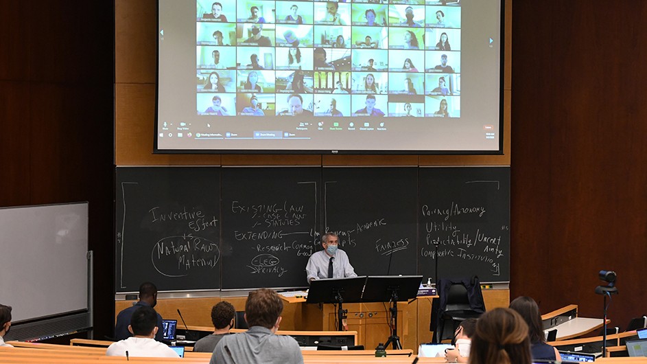 Photo by Eileen Barroso for Columbia Law School Students sit in a classroom with masks on while other students are on Zoom.